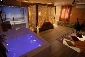 een groot bad in een kamer met een bed en een bank bij Capsule Marrakech I Chicha I Sauna I Balnéo I Console PS5 I Cinéma in Trith-Saint-Léger