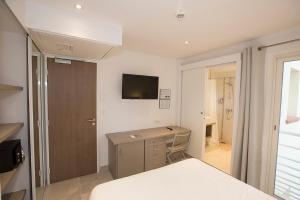 een slaapkamer met een bed, een bureau en een televisie bij Hôtel de la Plage - HDLP in Bormes-les-Mimosas