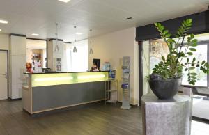 a lobby with a counter with a potted plant at Aarau West Swiss Quality Hotel in Oberentfelden