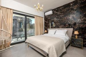 a bedroom with a bed and a large window at Rans Luxury Villas & Suites in Corfu with swimming pool in Gouvia