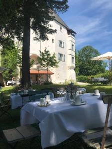 een tafel met witte tafelkleden en stoelen voor een gebouw bij Schloss Amerang in Amerang