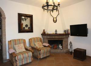 a living room with two chairs and a fireplace at Finca el Abuelo Manuel in Vejer de la Frontera