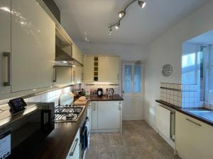 a kitchen with white cabinets and a stove top oven at 1 Lathom Ave - Parking, 2 Bathrooms, Comfortable, Welcoming, Nice Area in Morecambe +54 photos