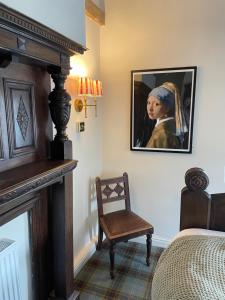 a bedroom with a fireplace and a painting of a girl at Beck Hall in Malham