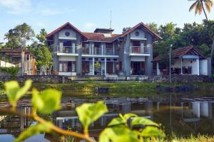 a house with a pond in front of it at Hibiscus Earth Private Pool Villa A CGH Earth SAHA Experience in Kumarakom