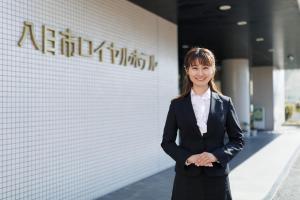 a woman in a suit standing in front of a building at Yokaichi Royal Hotel in Yōkaichi