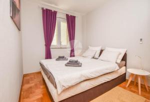 een slaapkamer met een groot bed met paarse gordijnen bij Apartment Amethist in Biograd na Moru