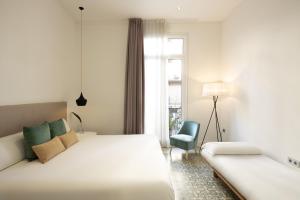 
a hotel room with a bed, chair, and nightstand at Forget Me Not in Barcelona
