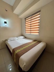 a bedroom with a large bed with a window at Eon Centennial Express Hotel in Iloilo City