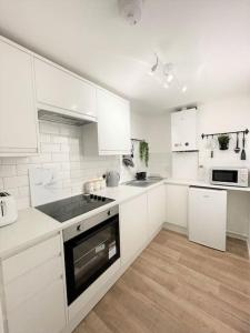 a white kitchen with white cabinets and a stove top oven at Central, Bright & Spacious Apartment - Parking Included in Bournemouth