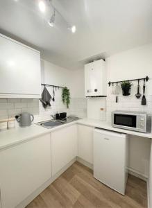 a white kitchen with a sink and a microwave at Central, Bright & Spacious Apartment - Parking Included in Bournemouth