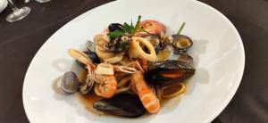 un plato blanco de comida con mejillones y camarones en Hotel Ristorante La Ripa en Fiuggi