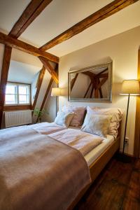 a large bed in a room with wooden beams at Baroque chaplain house Kaplanka 1796 A. D. - historical luxury apts in Bohemian Paradise in Železný Brod
