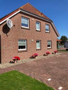 a brick house with potted plants in front of it at Ferienwohnungen Koch OG adult only in Wangerland