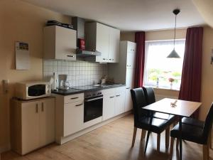 a kitchen with white cabinets and a table and a window at Ferienwohnungen Koch OG adult only in Wangerland