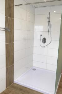 a bathroom with a shower with white tile at Ferienwohnungen Koch OG adult only in Wangerland