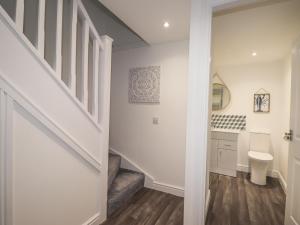 a white bathroom with a staircase and a toilet at Eider Cottage in Buckie +26 photos