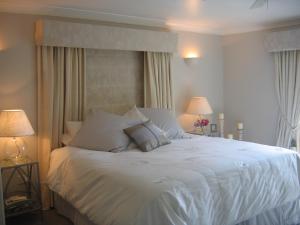 a bedroom with a white bed with two lamps at Spinneycross in Corsham
