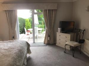 a bedroom with a bed and a television and a patio at Spinneycross in Corsham