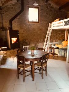 a wooden table and chairs in a room with a fireplace at Petite Maison pleine nature in La Bastide-Pradines