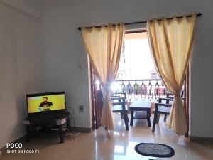 sala de estar con TV, mesa y ventana en 2 bhk Calangute - Baga road Saldanha Kyle Gardens en Calangute