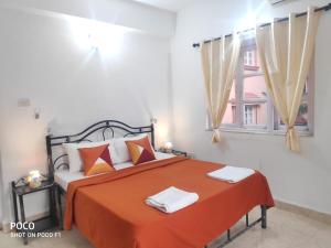 sypialnia z łóżkiem z pomarańczową pościelą i oknem w obiekcie 2 bhk Calangute - Baga road Saldanha Kyle Gardens w mieście Calangute