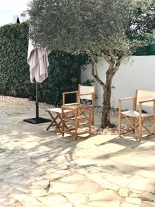 a group of chairs and an umbrella next to a tree at Chalet La Rosa in Cala Blanca