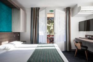 ein Hotelzimmer mit einem großen Bett und einem Schreibtisch in der Unterkunft Hotel SPA Plage St Jean in La Ciotat