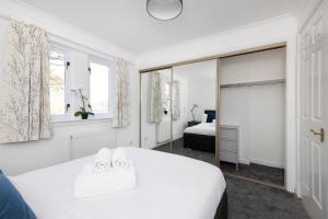 Habitación blanca con cama y espejo en ALTIDO Bright 3-bed flat overlooking The Clyde, en Glasgow