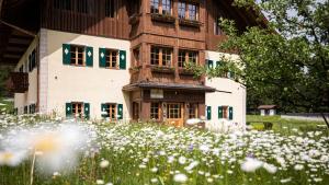 a building with a field of flowers in front of it at Natura Boutique Chalet Wellness SPA in Dobbiaco