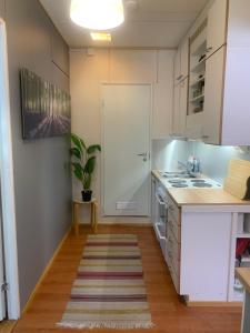 a kitchen with white cabinets and a sink at Bungalow house flat in Rekola 33m2 in Vantaa