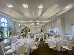 a banquet hall with white tables and chairs at Pałac w Rymaniu in Rymań