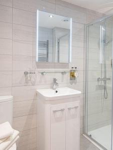 a white bathroom with a sink and a shower at Gwbert Hotel in Cardigan