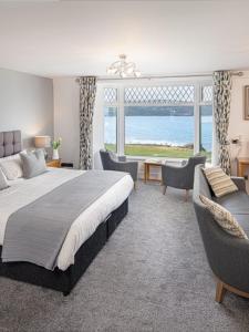 a bedroom with a bed and chairs and a large window at Gwbert Hotel in Cardigan