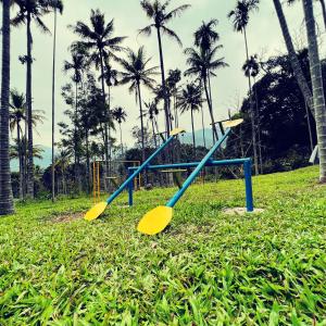 a playground in a field of grass with palm trees at Davis Farm House in Maraiyūr