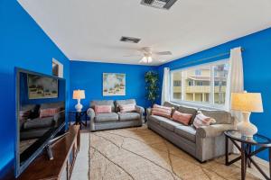 uma sala de estar azul com dois sofás e uma televisão em Regency Cabanas #D4 em Pensacola Beach