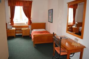 a bedroom with a bed and a desk and a mirror at Kaštieľ AGATKA in Chorvátský Grob