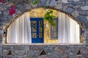 a stone building with a blue door and windows at Alexandros by the Beach - Serifos in Livadakia