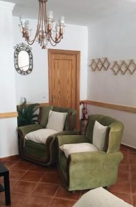 una sala de estar con 2 sillas verdes y una lámpara de araña en El Rinconcito de Nadia, en Benaocaz