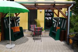 un patio con sillas y una sombrilla verde en Ferienhaus am Saaler Bodden, en Neuendorf