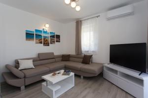 ein Wohnzimmer mit einem Sofa und einem Flachbild-TV in der Unterkunft VILLA HONEY, Seget - Trogir in Seget Vranjica