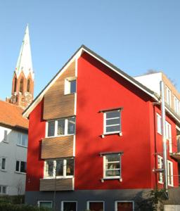 un bâtiment rouge avec une église en arrière-plan dans l'établissement Ole & Trude, à Kiel
