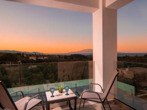 einen Balkon mit einem Tisch und Stühlen sowie einem Sonnenuntergang in der Unterkunft Vatia Villas in Tragaki