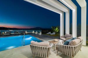 a patio with a pool and chairs and a table at Vatia Villas in Tragaki