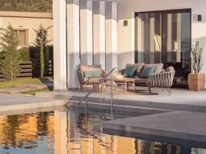 two chairs and a table next to a swimming pool at Vatia Villas in Tragaki