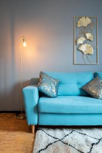 a blue couch in a living room with a lamp at Grand T2 à 8mn de Lille et Stadium Terrasse et parking privé in Villeneuve d'Ascq