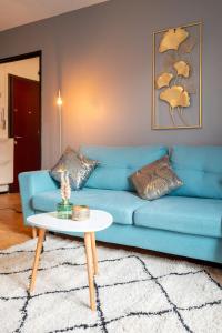 a blue couch in a living room with a table at Grand T2 à 8mn de Lille et Stadium Terrasse et parking privé in Villeneuve d'Ascq