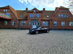 a black car parked in front of a brick building at Hotel Stokkegaarden's BnB & Apartments in Stokkemarke