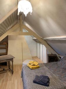 een slaapkamer met een bed en een tafel op zolder bij LA MAISON DE FAMILLE in Néville