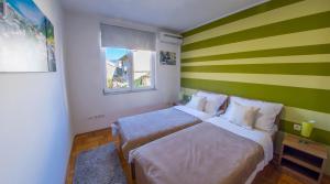 a bedroom with a green and white striped wall at Mila Apartments in Mostar